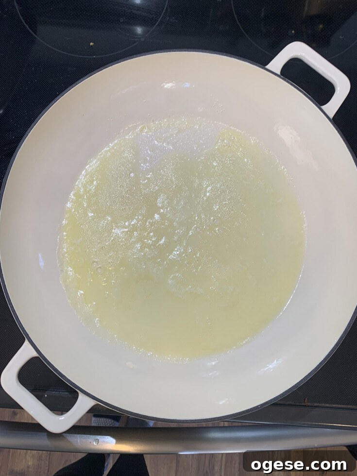 Melted butter in white pan on black stove.