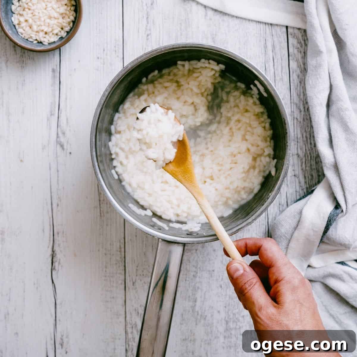 cooked rice in a pot being stirred by a wooden spoon.