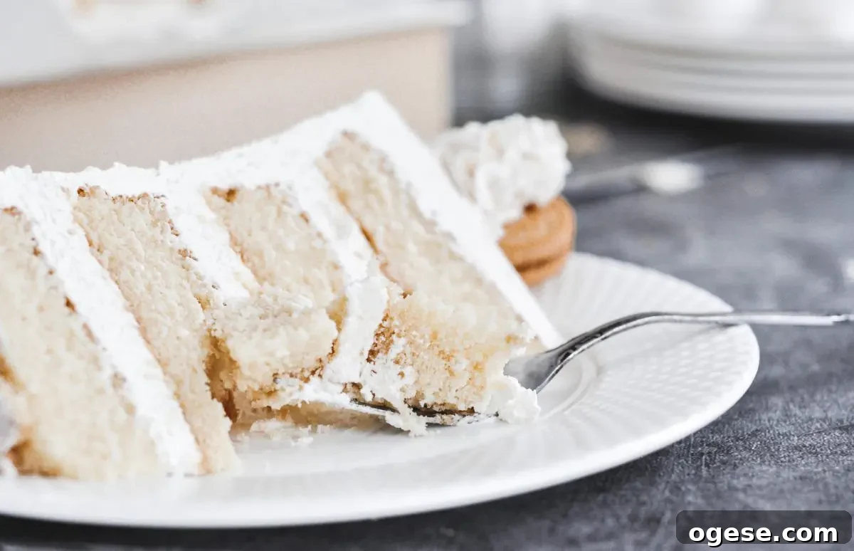 A slice of vanilla cake with a fork full of cake on the plate