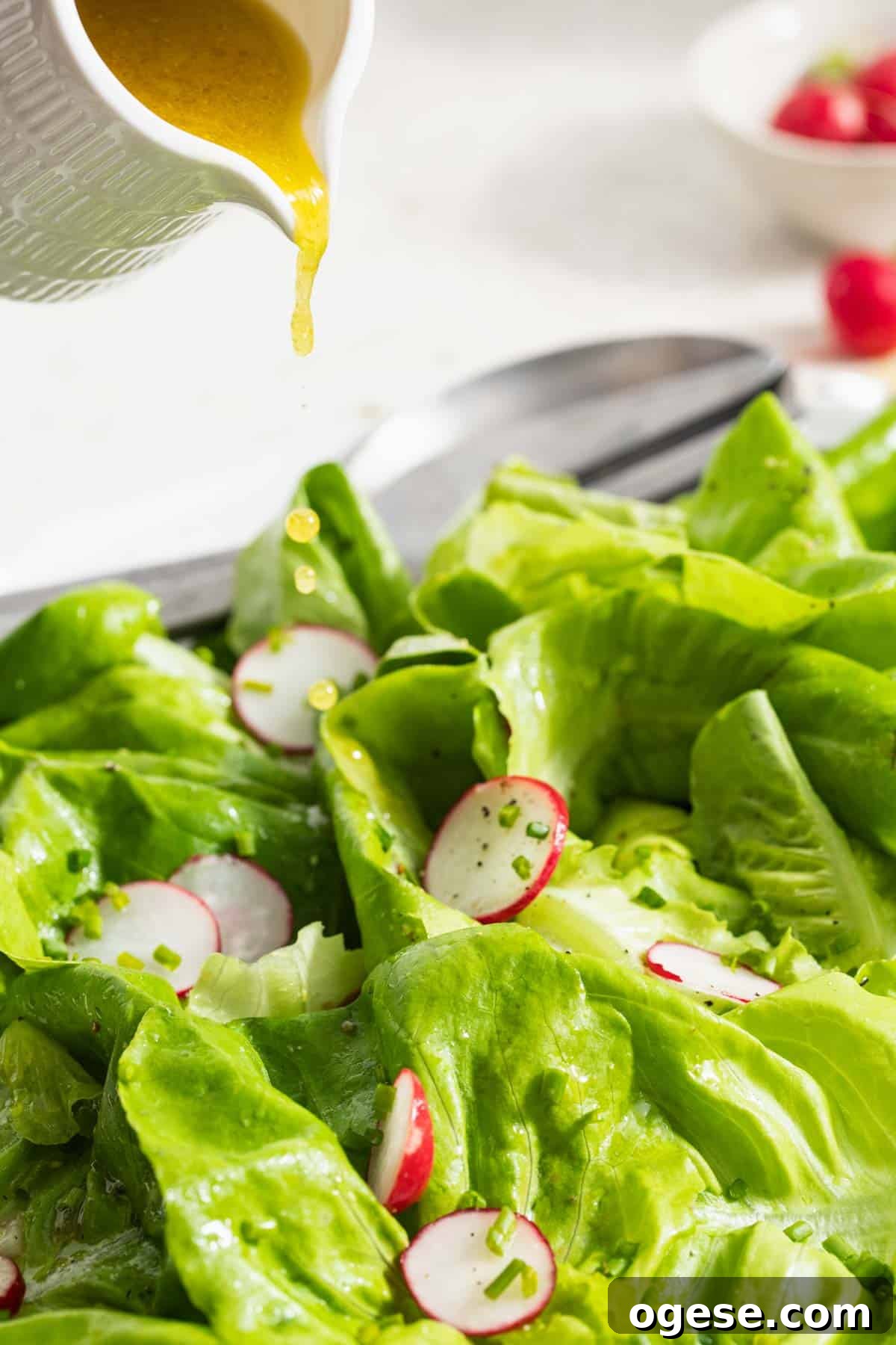 Crisp Bibb Lettuce Salad with Lemon Vinaigrette 6 Pouring dijon dressing on a side salad.