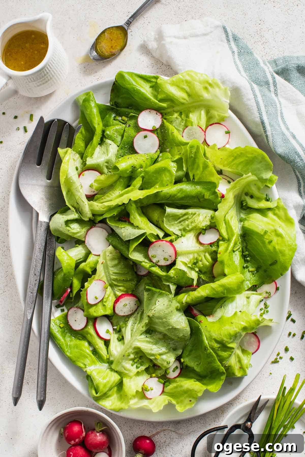 Crisp Bibb Lettuce Salad with Lemon Vinaigrette 8 A bibb lettuce salad with two large serving utensils next to it.