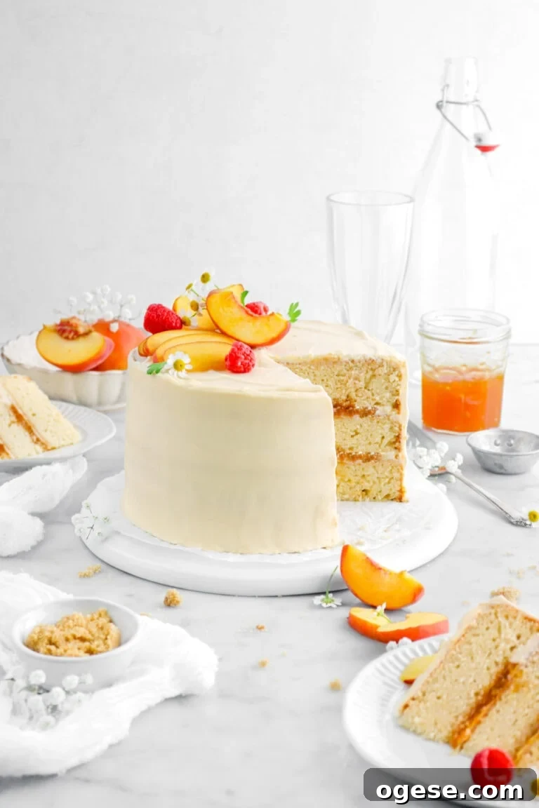 peach cake with two slices in front and behind on white plates with peaches and flowers around