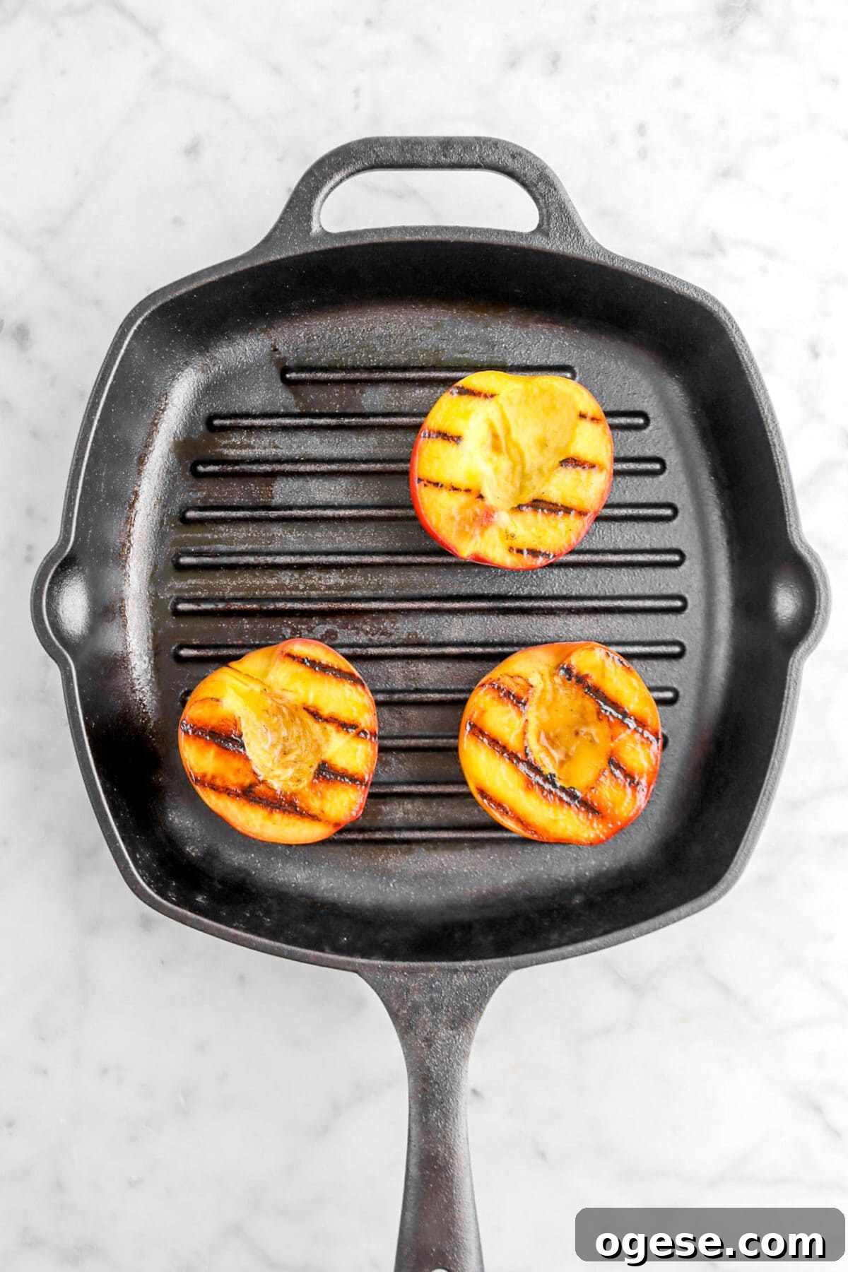 three grilled peaches on grill pan.