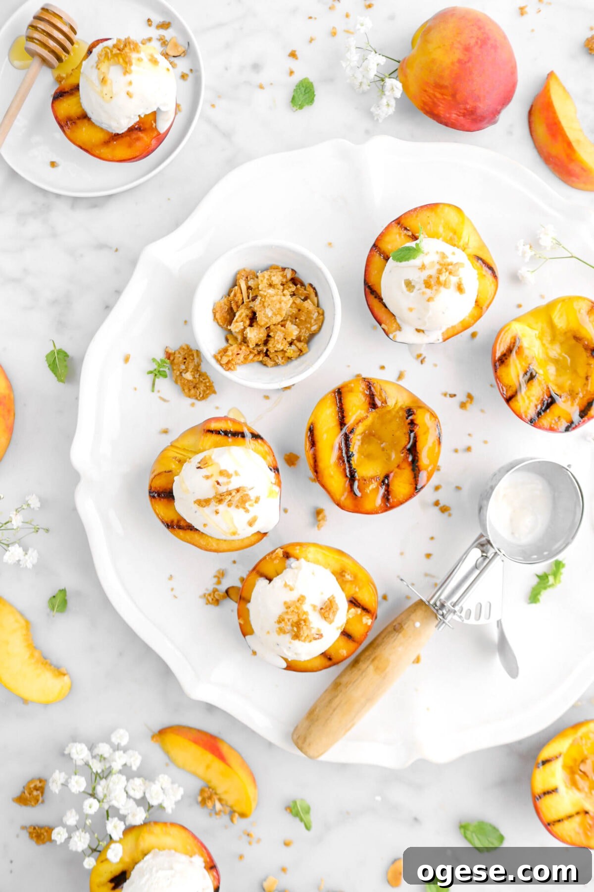 photo of 3/4 of round white platter with five grilled peaches on it, an ice cream scoop, and more peaches around