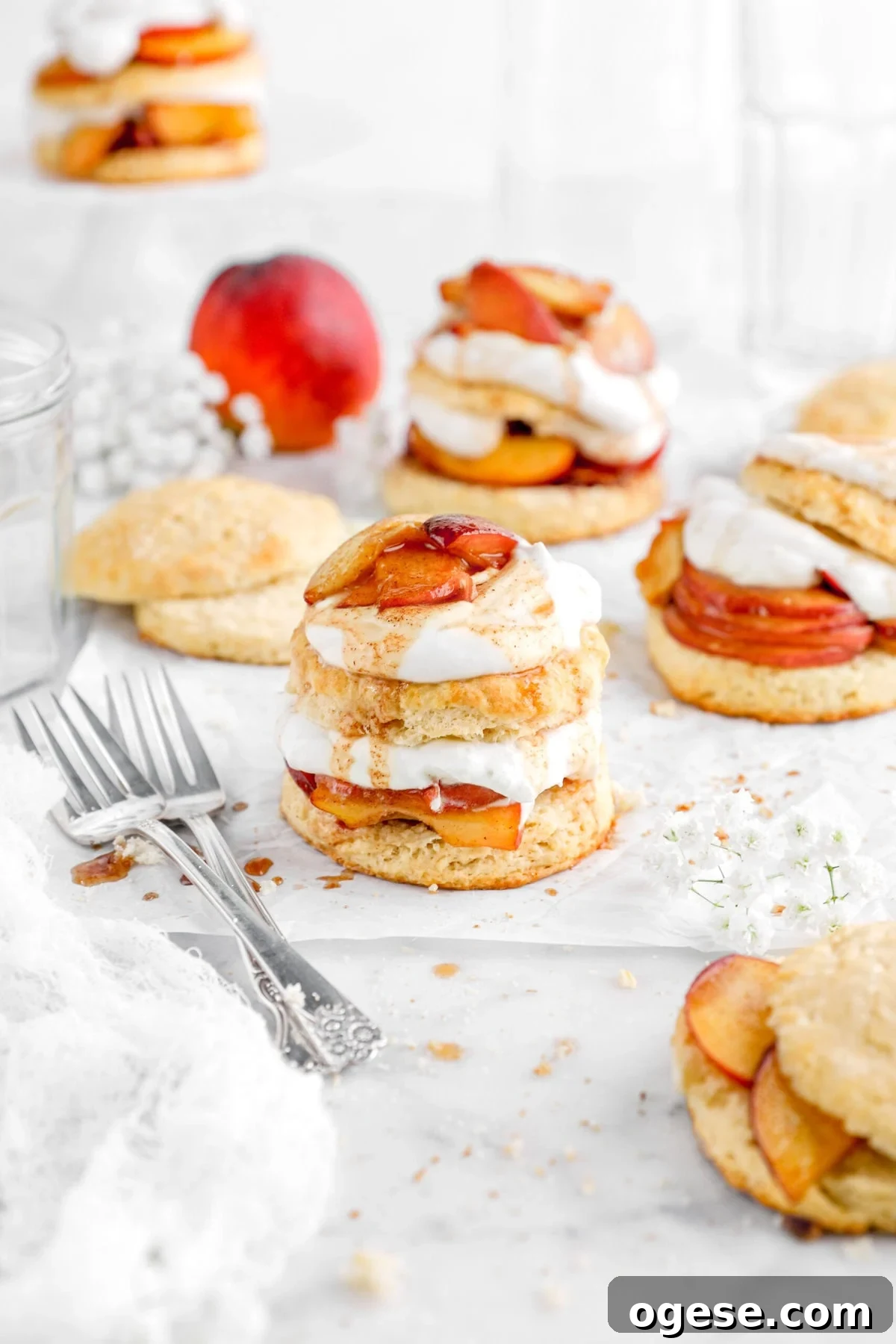 peach shortcake on parchment paper with three more behind and two forks beside.