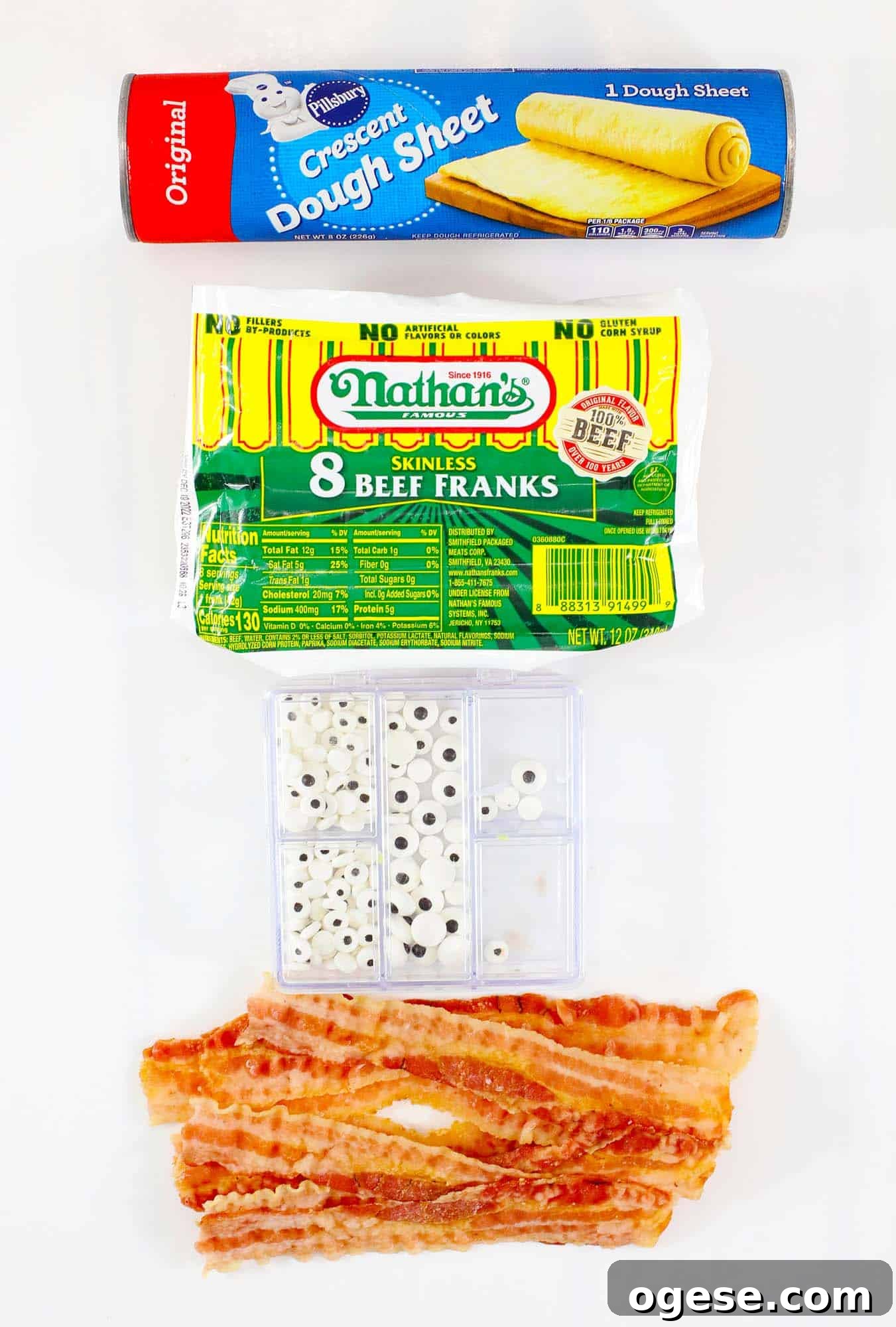 Ingredients needed to make air fryer mummy hot dogs including crescent dough, beef franks, candy eyeballs, and crispy bacon