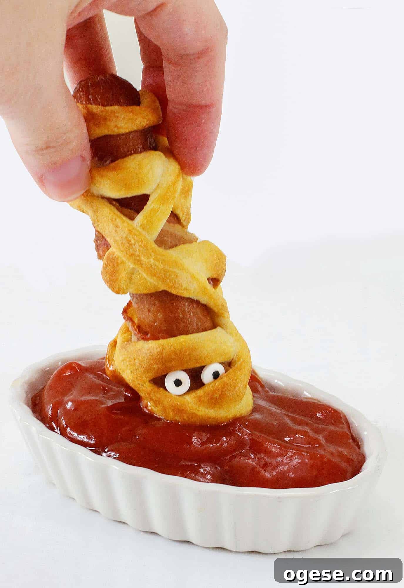 Dipping a mummy hot dog in ketchup