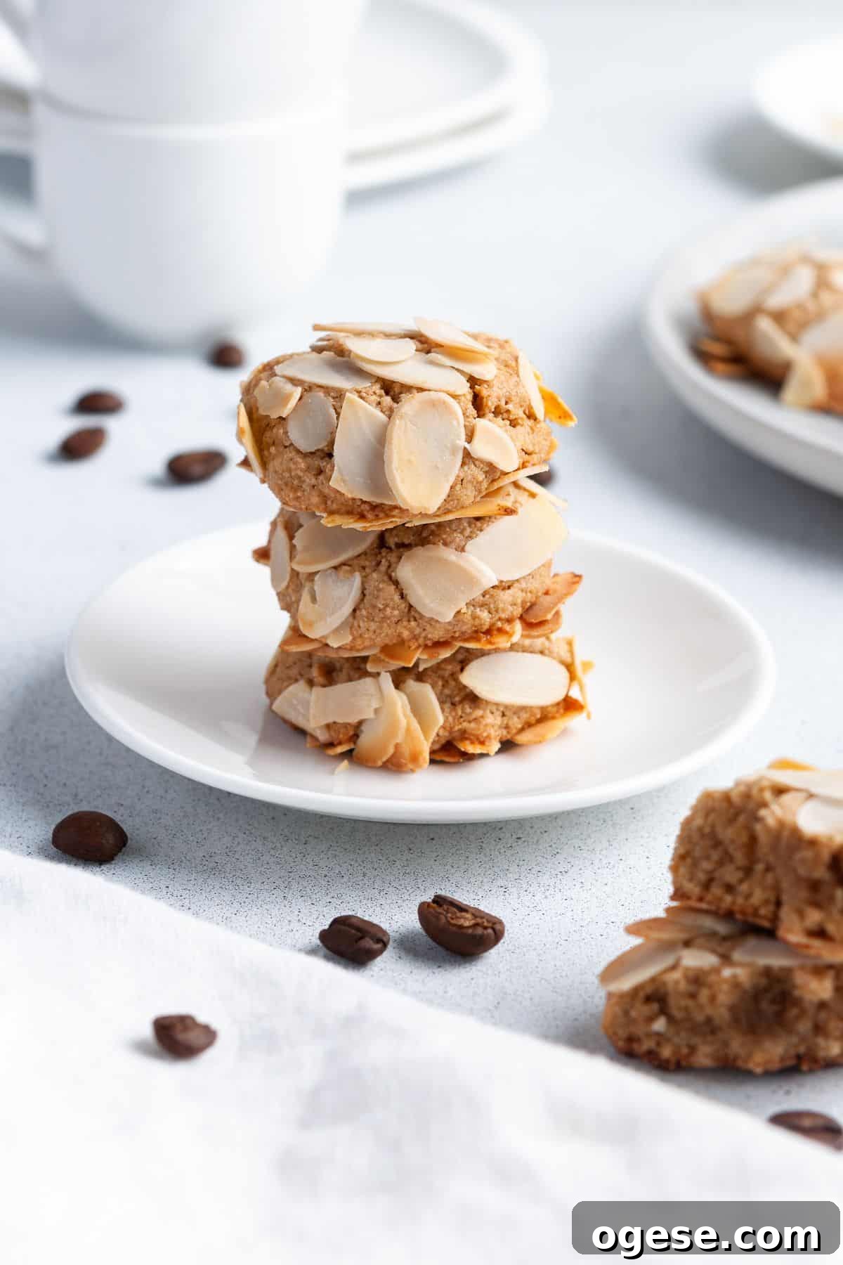 Stack of three cookies sitting on a small round white plate, with some coffee beans around the edge.