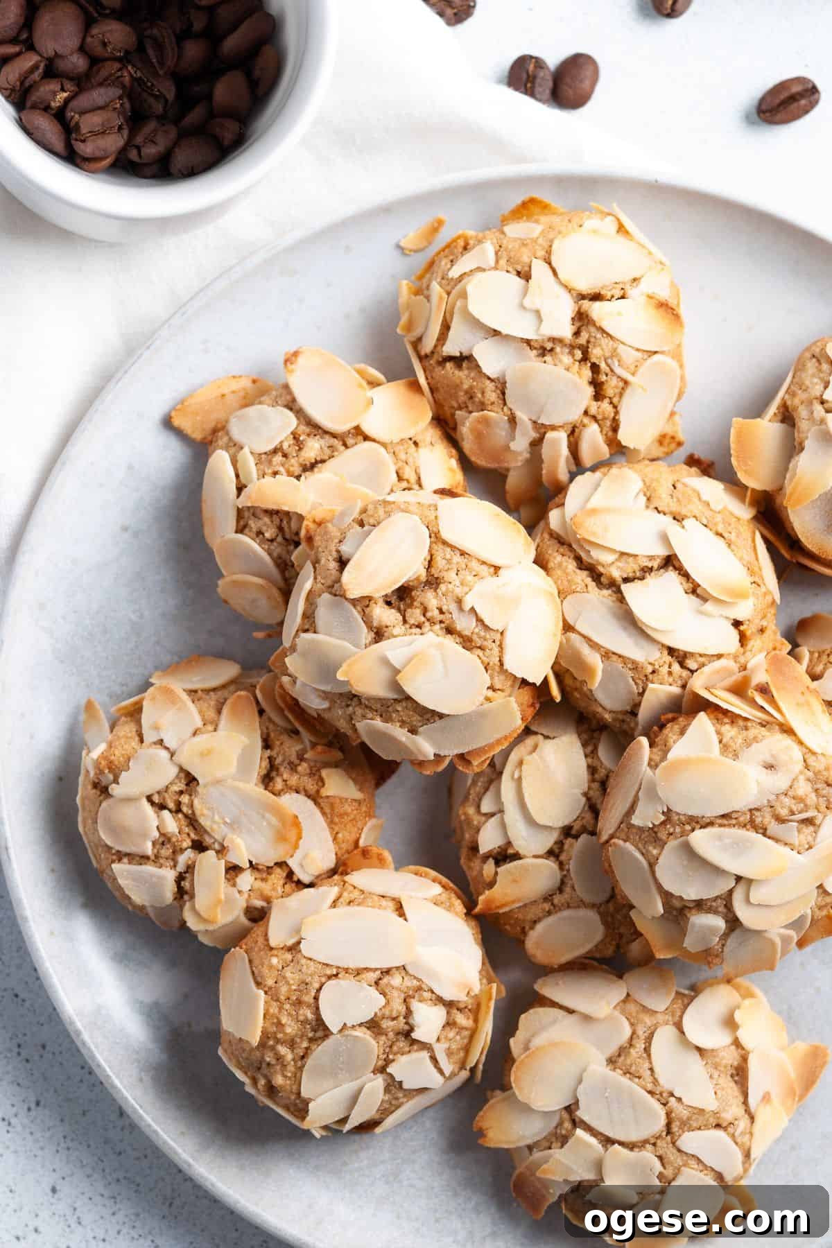 Round plate topped with cookies, sitting on a white cloth with some coffee beans around the edge.