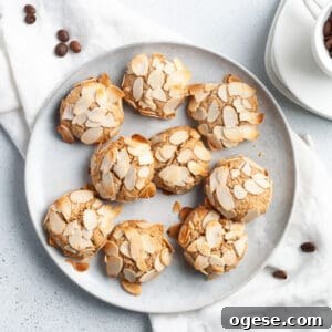 Round plate topped with cookies, sitting on a white cloth with some coffee beans around the edge.