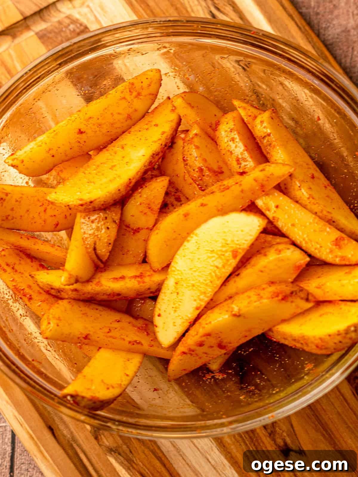 Potato wedges in a bowl with spices.