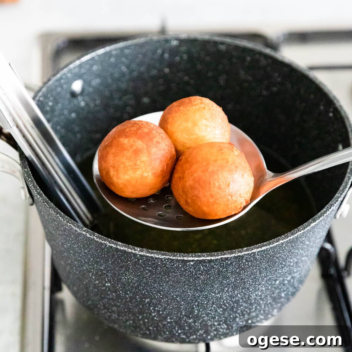 Madeleine-Style Tofu Doughnuts: Light, Protein-Packed Treats 8 donut holes being taken out of the hot oil with slotted spoon.