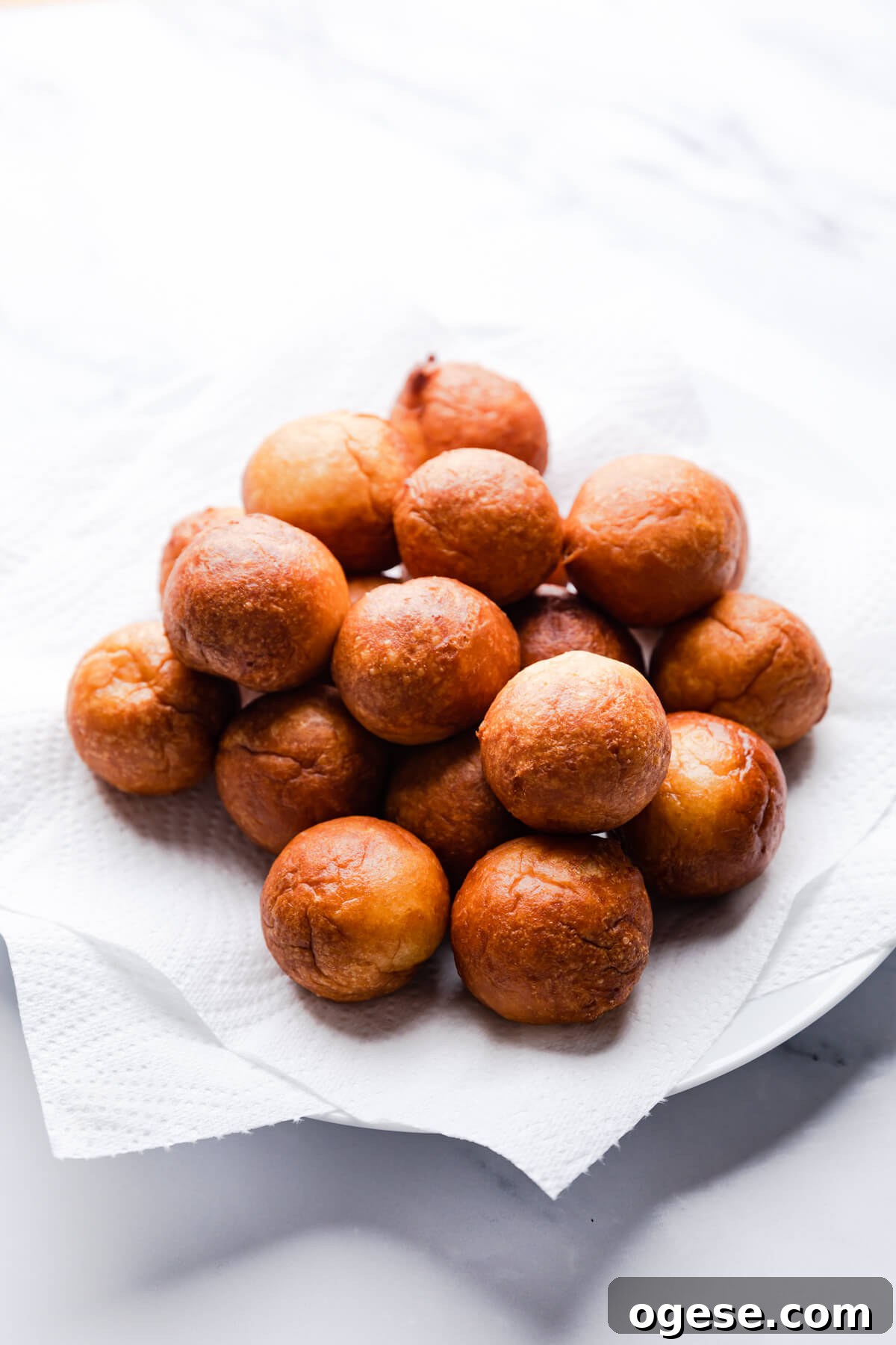 Madeleine-Style Tofu Doughnuts: Light, Protein-Packed Treats 9 tofu mini doughnuts balls on a plate with paper towel.