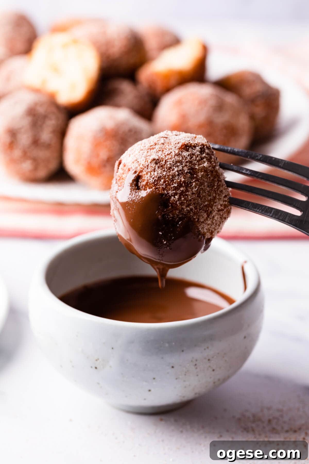 Madeleine-Style Tofu Doughnuts: Light, Protein-Packed Treats 10 tofu doughnut being dipped in melted chocolate.
