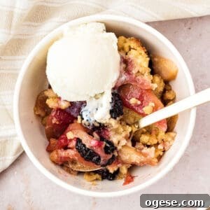 White bowl of apple blackberry crumble with ice cream. Beige background.