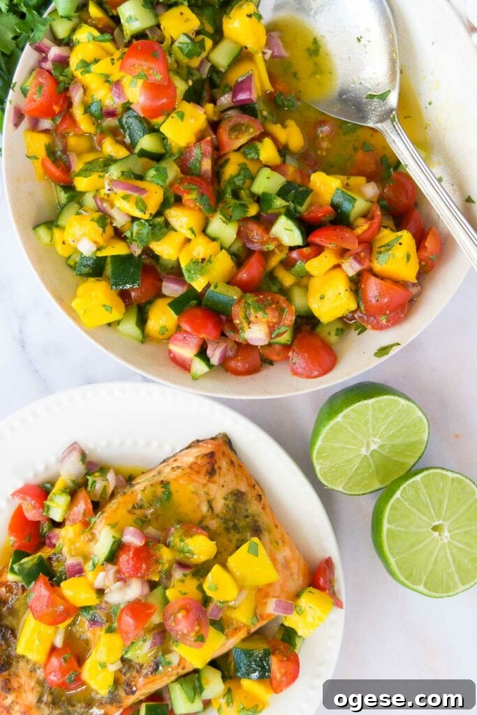 a bowl of cucumber mango salsa next to a plate of salmon