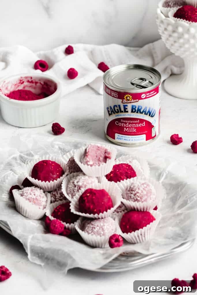 45 degree angle shot of a platter of raspberry brigadeiros. A can of sweetened condensed milk sits in the background.