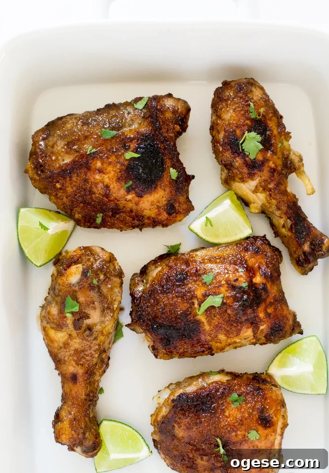 Oven-Baked Jamaican Jerk Chicken Recipe 8 Oven baked jerk chicken in a white dish with lime wedges.