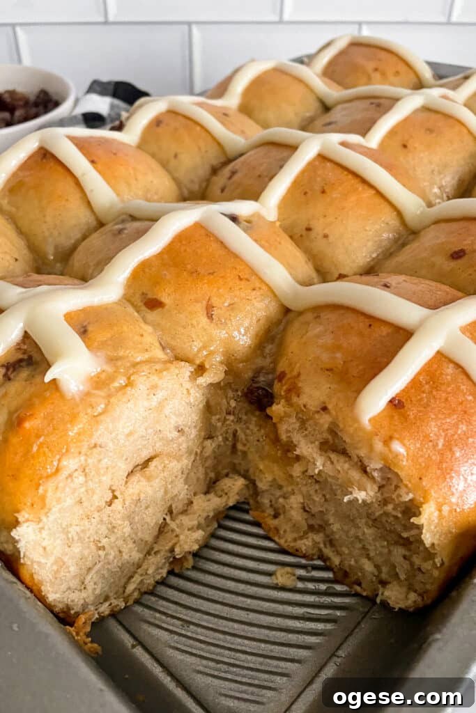 traditional hot cross buns baked and ready to eat.  Corner bun removed to show texture of the inside of the rolls