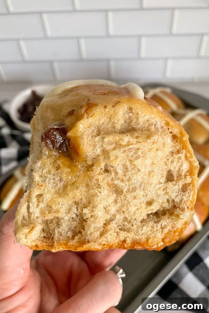 close up shot of a hot cross bun being held up to show the fluffy texture of the bun