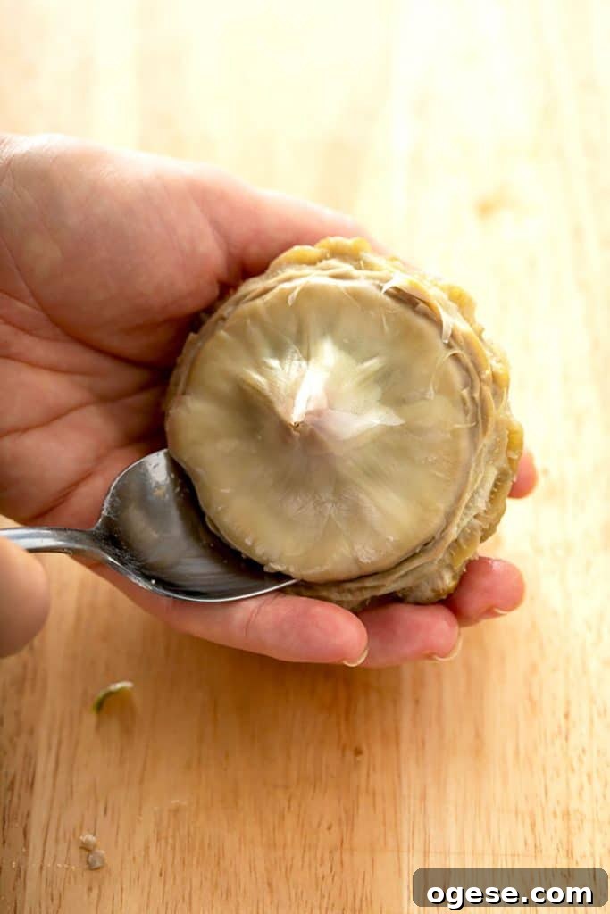How to Cook Artichokes: Steamed and Roasted Methods 15 scraping off the choke of an artichoke with a spoon