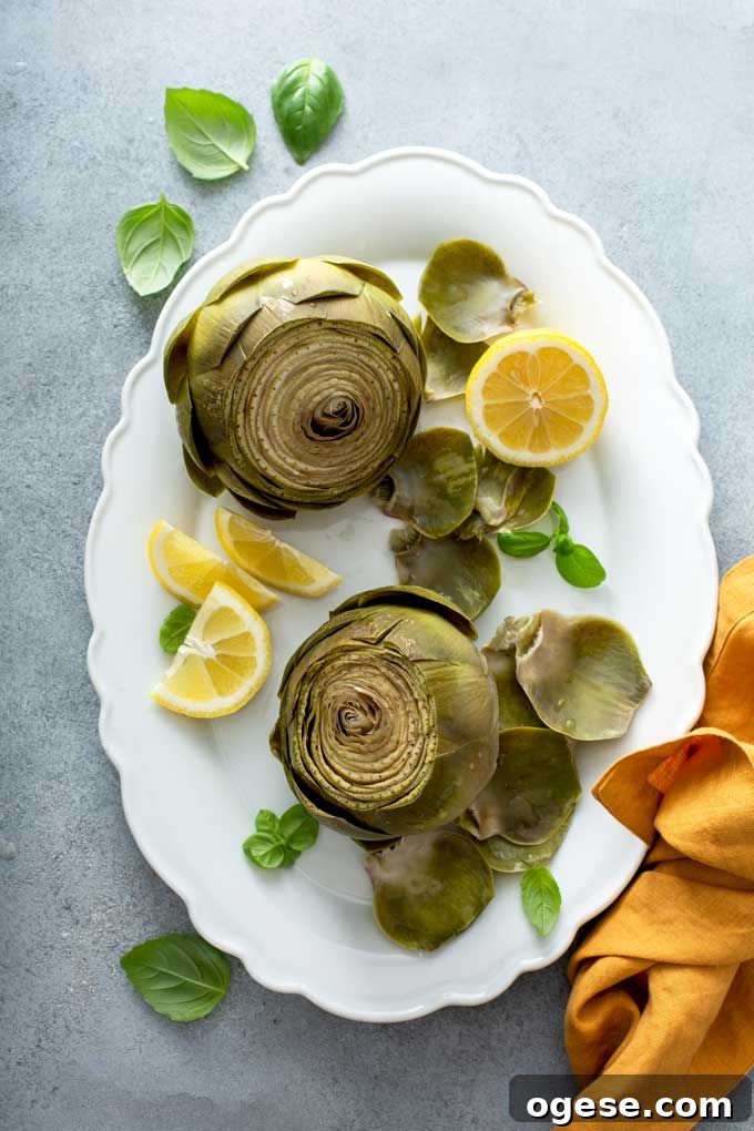 How to Cook Artichokes: Steamed and Roasted Methods 17 Artichokes on a white platter with lemon slices