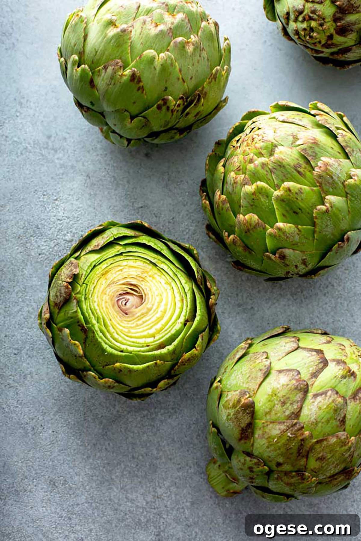 How to Cook Artichokes: Steamed and Roasted Methods 5 Artichokes on a gray surface.
