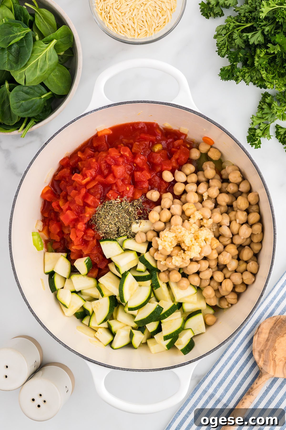 Hearty Vegetable Orzo Soup Recipe for Cozy Weeknights 5 Zucchini, diced tomatoes, garlic, Italian seasoning, and garbanzo beans are added to sauteed vegetables in a large pot.