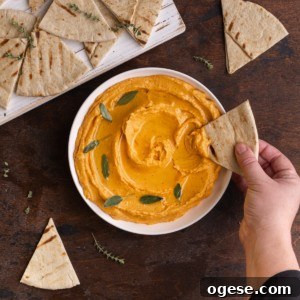 dipping a piece of pita bread into sweet potato hummus