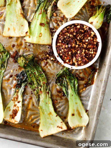 roasted bok choy on a sheet pan with red pepper flakes on top