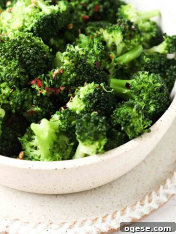 Blanched broccoli in a bowl with red pepper flake garnish.