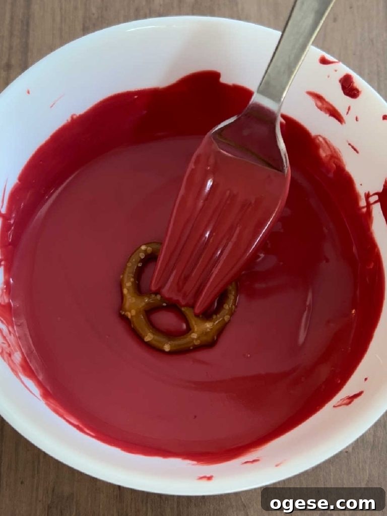 dip mini pretzel into melted red candy coating