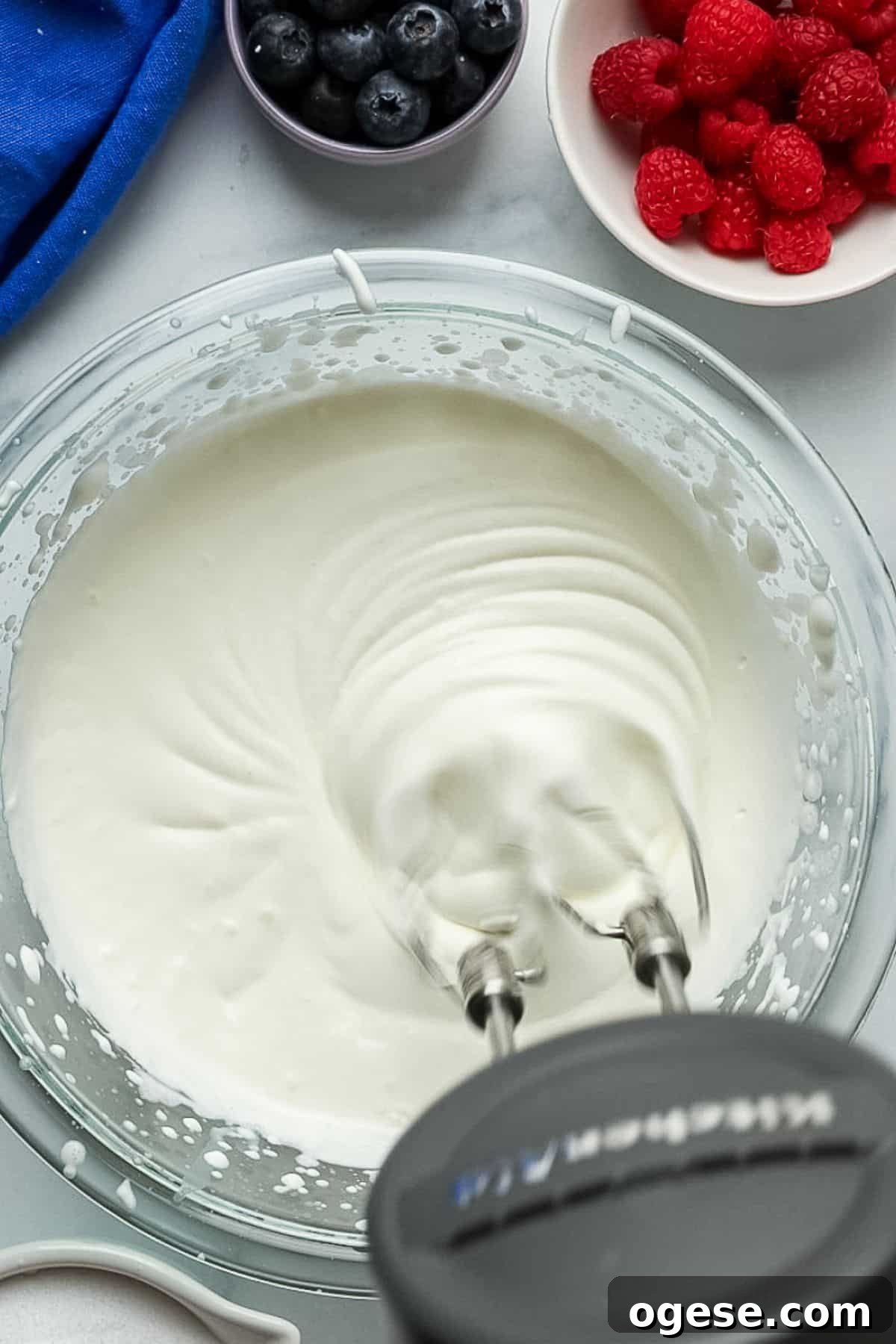 Heavy cream whipped to stiff peaks in a glass bowl using a hand mixer