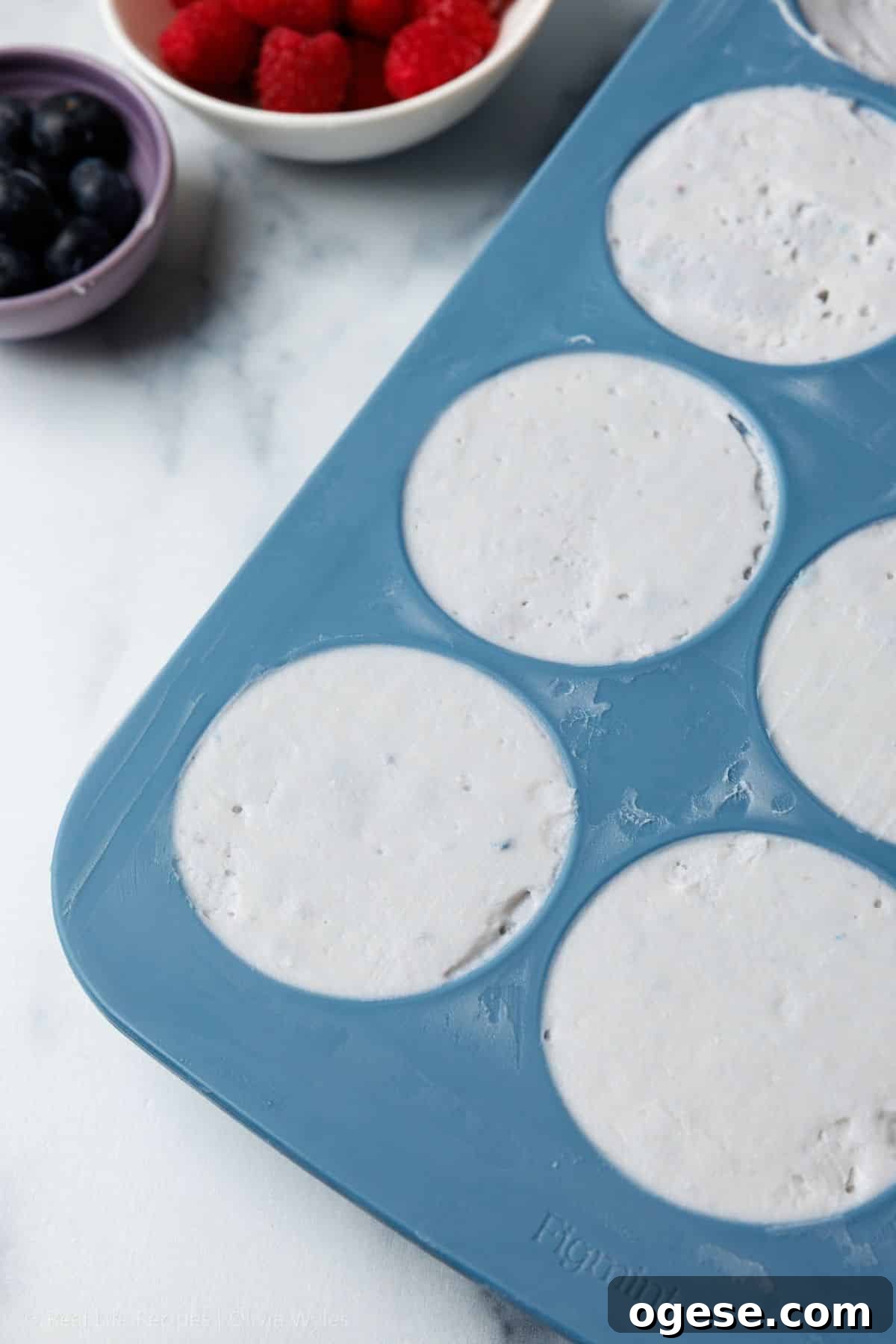 Cheesecake mixture portioned into a blue silicone muffin mold, ready to set in the fridge