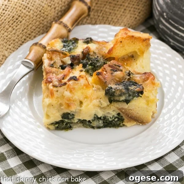 Gruyère and Spinach Strata Recipe for Brunch or Holiday Breakfast 2 Gruyere Spinach Strata slice on a white plate with a bamboo handle fork.