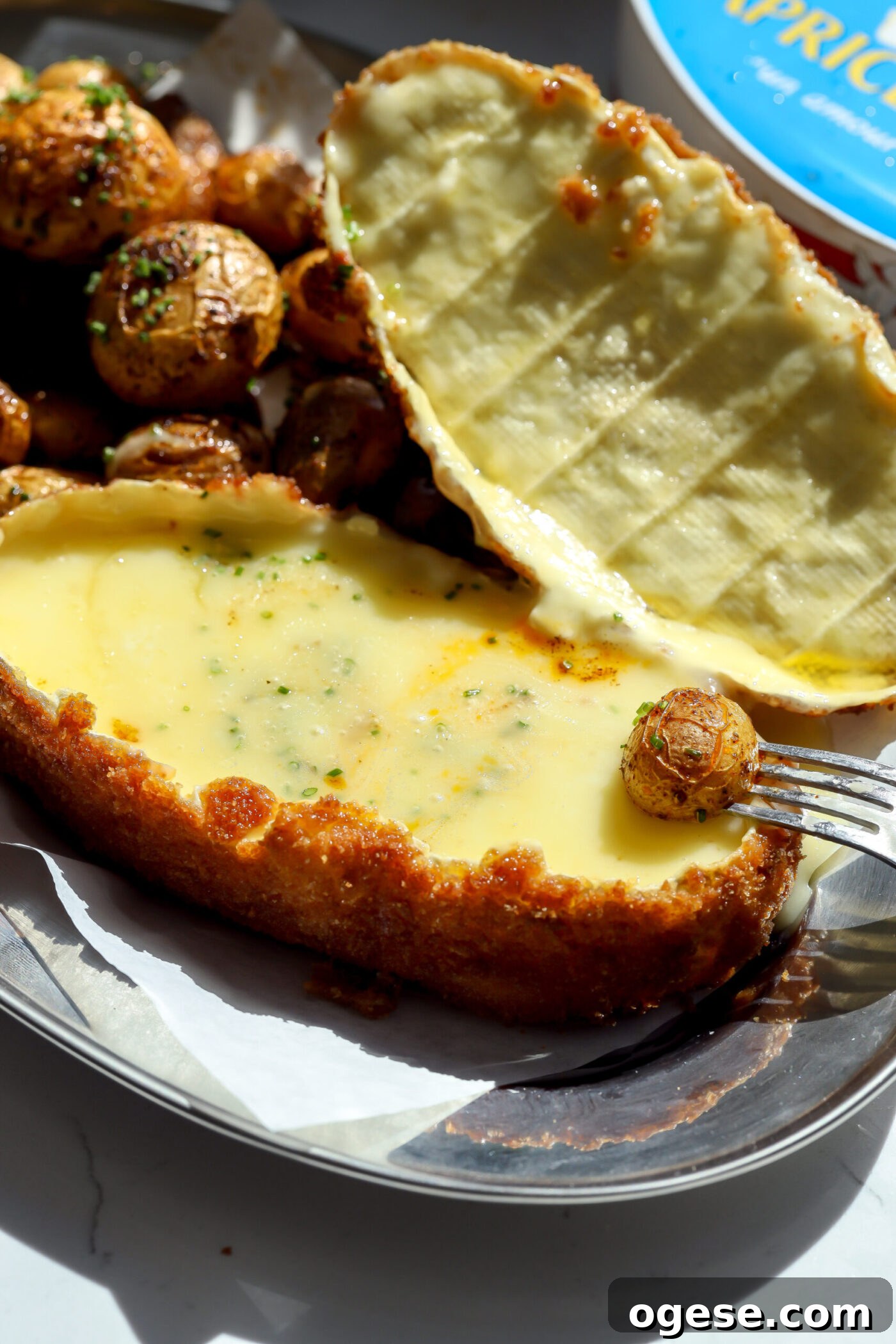Crispy Fried Cheese Wheel Recipe: Gooey Center, Crunchy Crust 5 Top lifted to reveal a creamy interior with a baby potato ready for dipping.