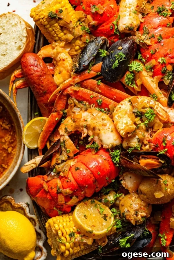 cajun seafood boil recipe on a large serving tray next to a bowl of seafood boil sauce, bread, and sliced lemons