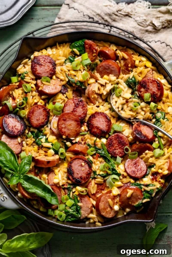 cajun orzo topped with sausage, fresh basil, and diced green onions in a skillet.
