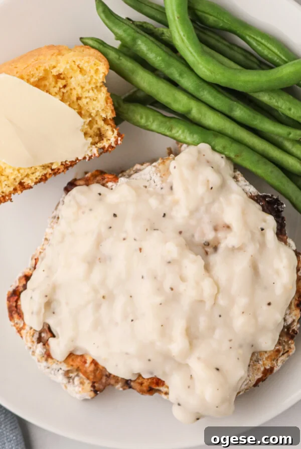 Crispy Air Fryer New York Strip Steak Recipe 12 Overhead shot of chicken fried steak made in the air fryer and served on a plate covered in gravy and served with green beans and a side of cornbread.