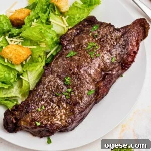 Crispy Air Fryer New York Strip Steak Recipe 13 Air Fryer New York strip steak on a white plate with a salad.