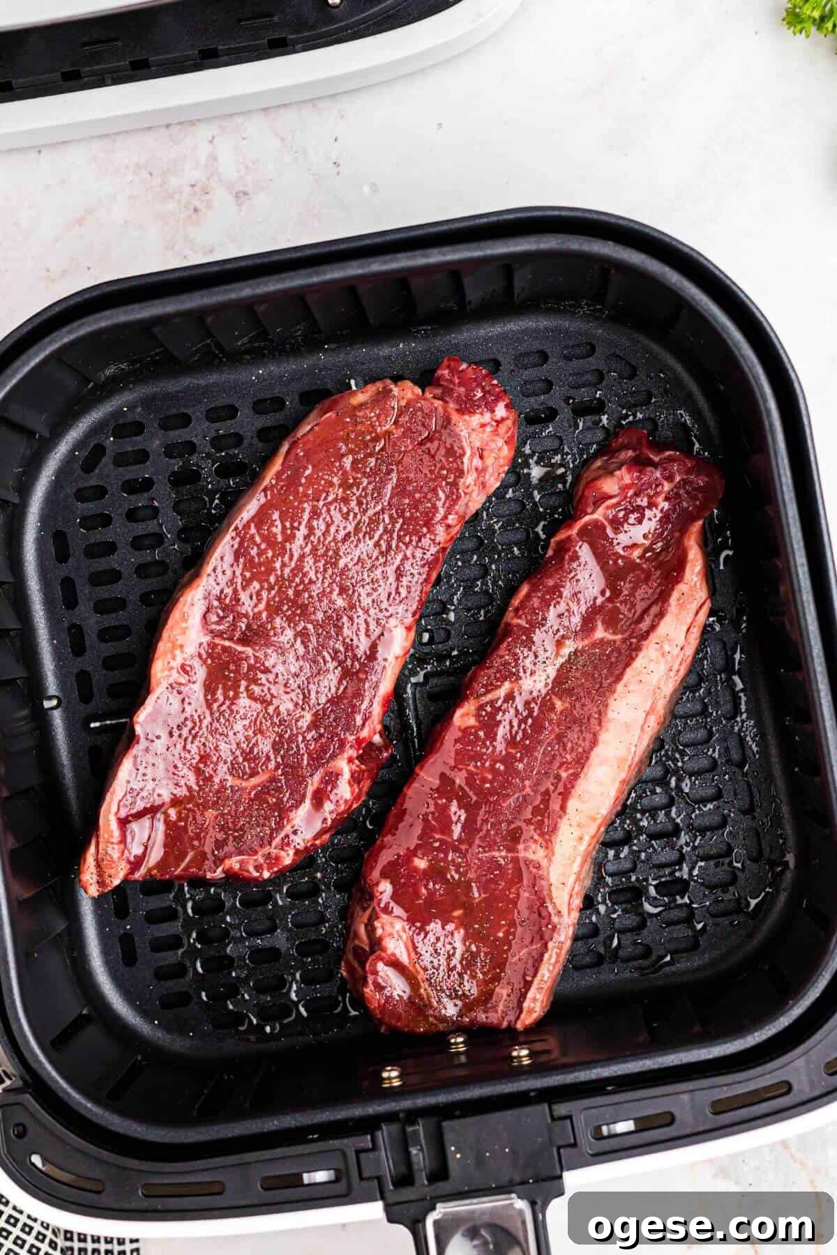 Crispy Air Fryer New York Strip Steak Recipe 6 Seasoned uncooked steaks in the air fryer basket.