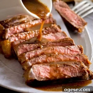 Sliced cooked steak with red wine jus being poured