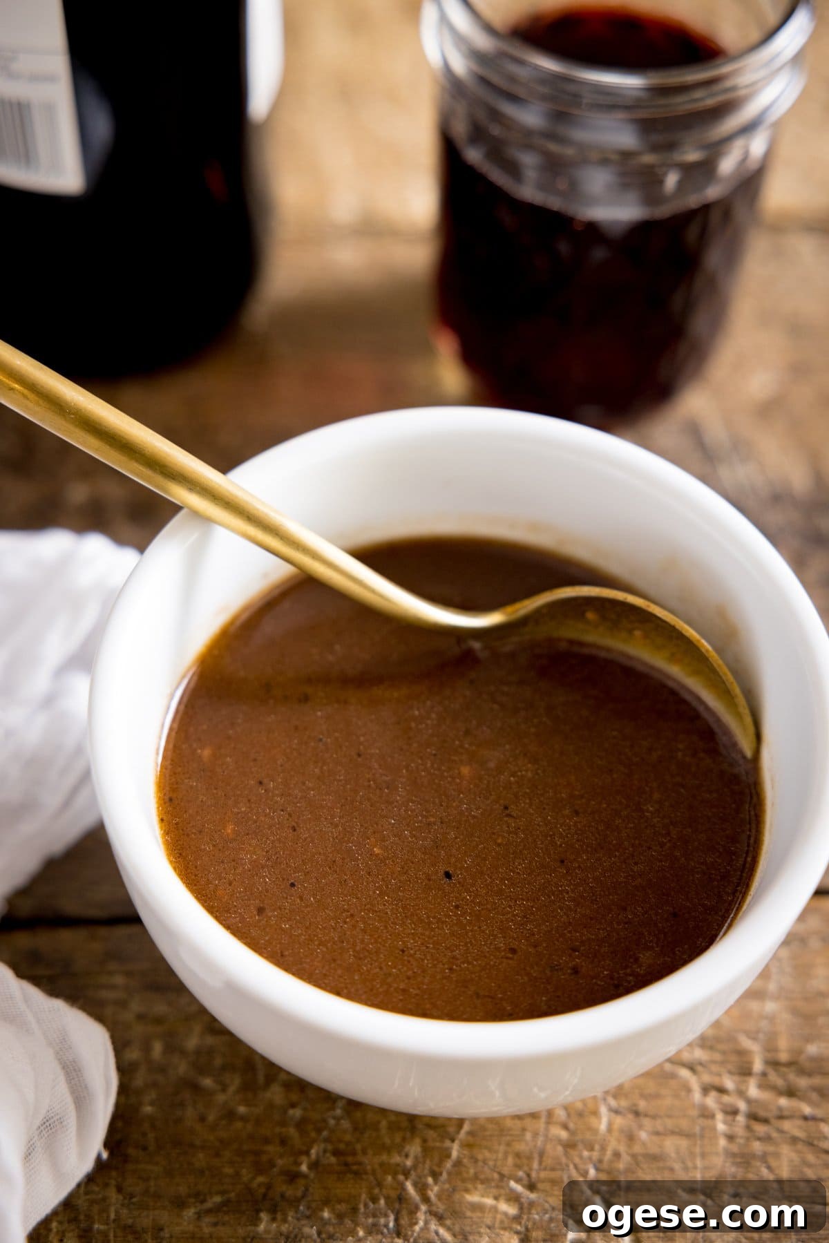 Rich Red Wine Jus Recipe for Steak and Roast 4 A white bowl of red wine jus being stirred with a spoon