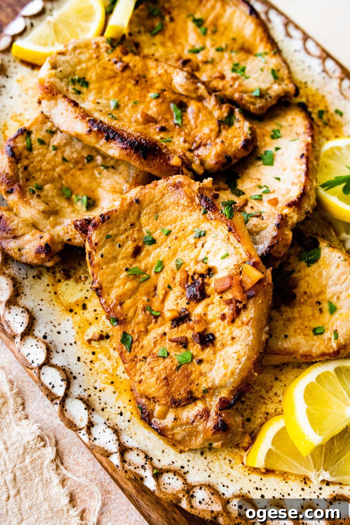 Perfectly Pan-Seared Thin Pork Chops: Quick Juicy Recipe 2 close up of the thin pork chops on a serving platter with lemon wedge.