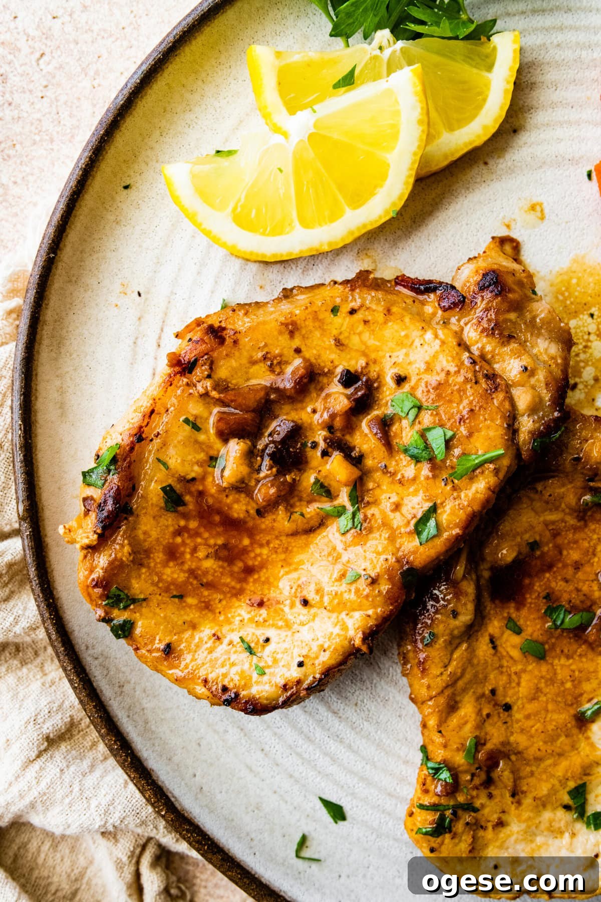 Perfectly Pan-Seared Thin Pork Chops: Quick Juicy Recipe 11 two juicy thin pork chops on a plate wit cooked carrots as a side dish.