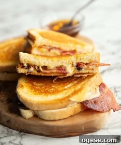 4 bacon grilled cheese halves on wooden board with small glass pot of maple syrup