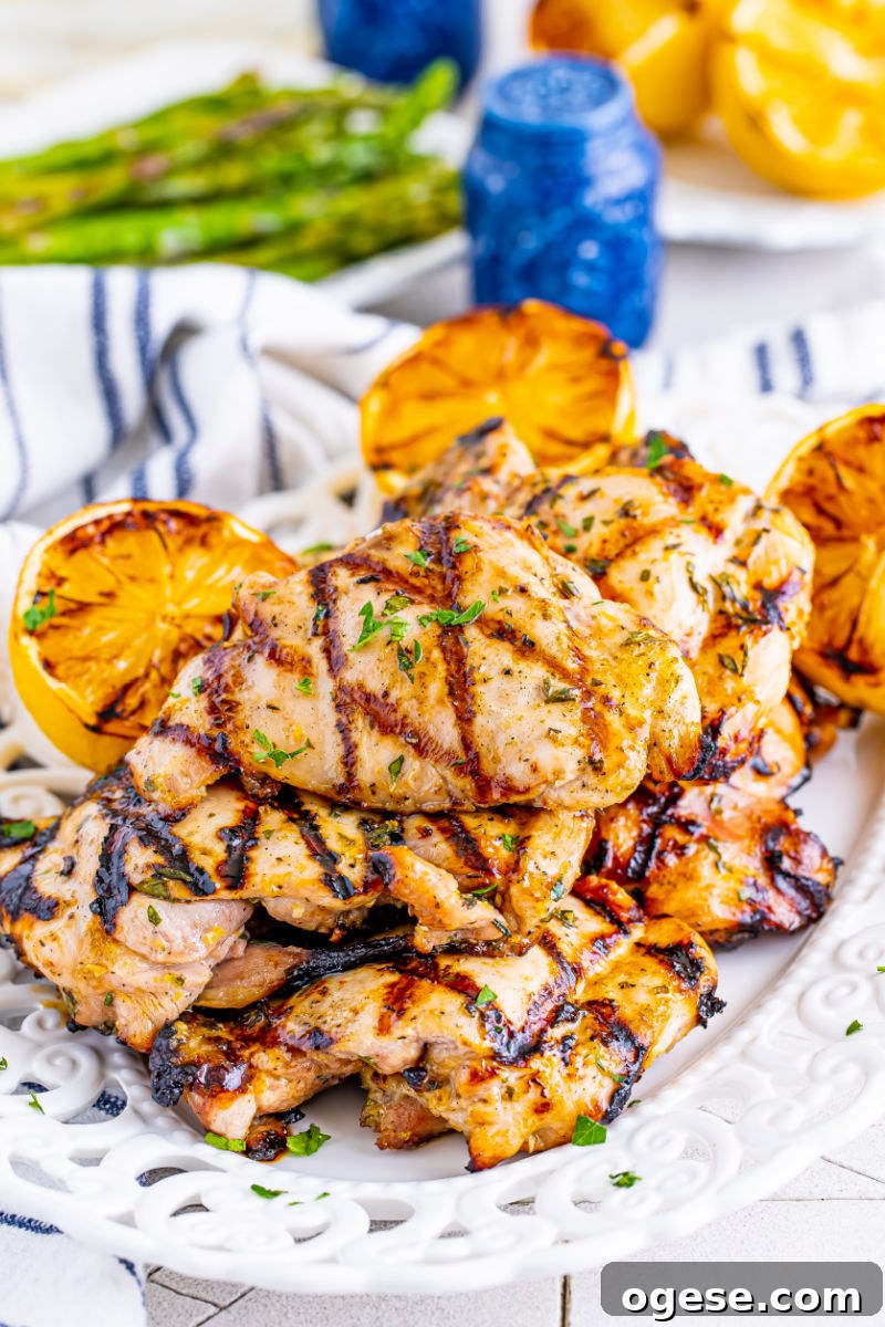serving platter of lemon garlic grilled chicken thighs next to a platter of asparagus
