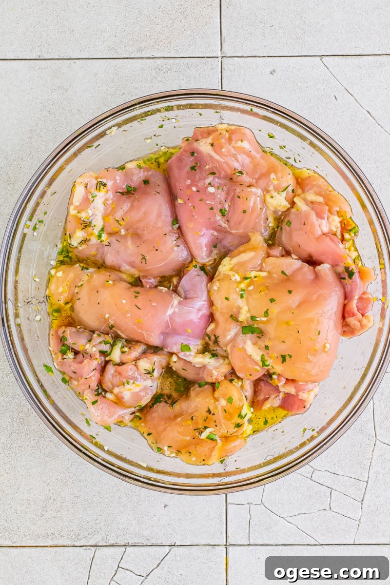 boneless skinless chicken things coated in lemon garlic marinade in a glass bowl