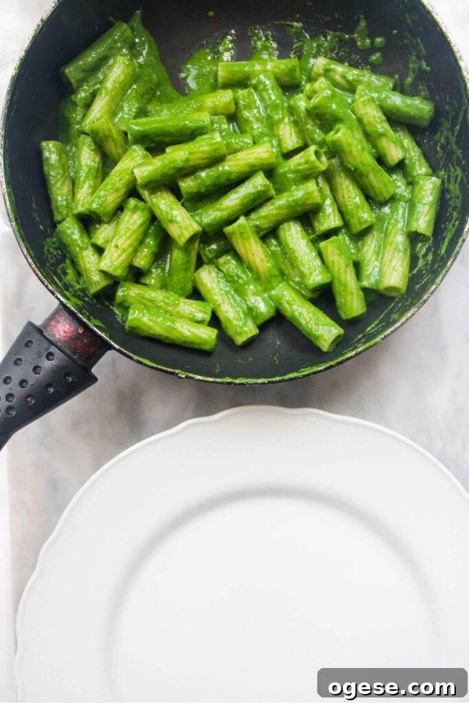 15-Minute Super Green Rigatoni Recipe for Quick Weeknight Dinner 12 Green pasta in a small pan with a white plate in front of it, ready to be served.