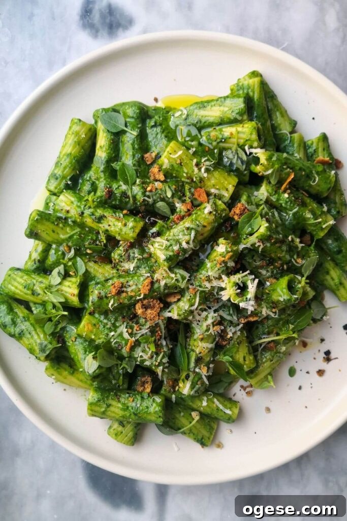15-Minute Super Green Rigatoni Recipe for Quick Weeknight Dinner 13 Green pasta sauce with rigatoni on a white plate, topped with grated parmesan, chilli oil and crispy pita crumbs.